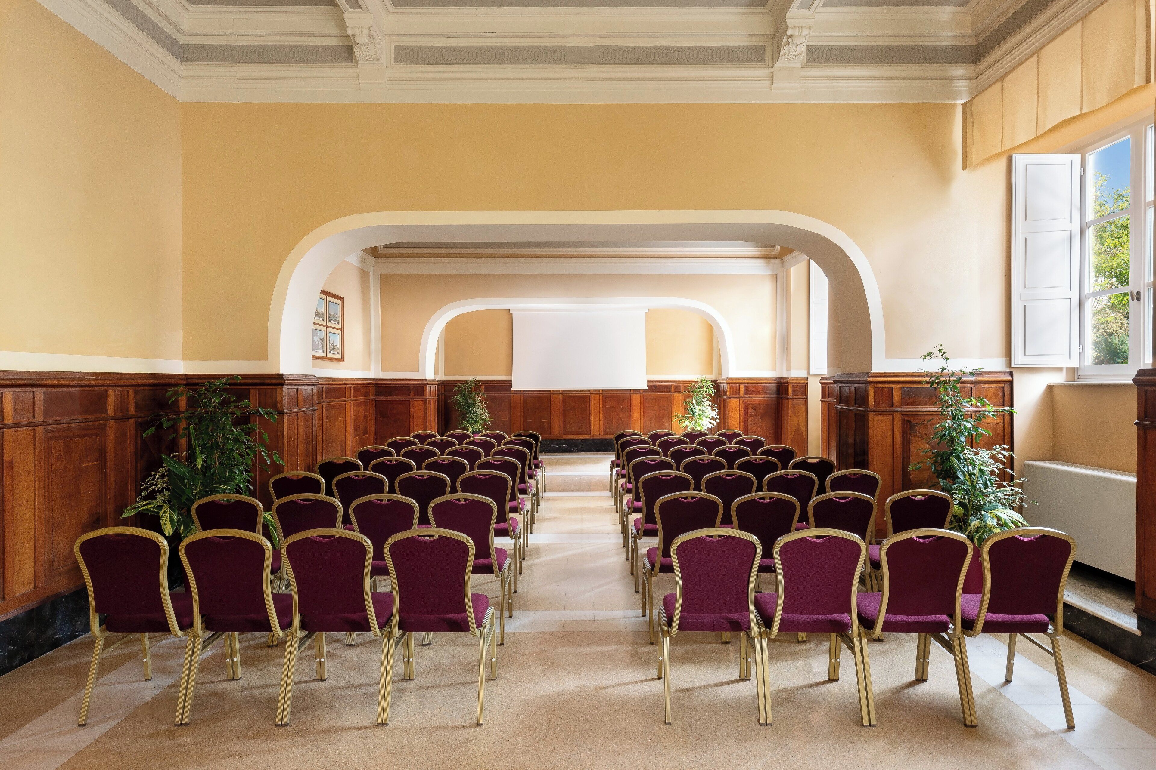 Un salón de conferencias con filas de sillas moradas y paneles de madera en las paredes.