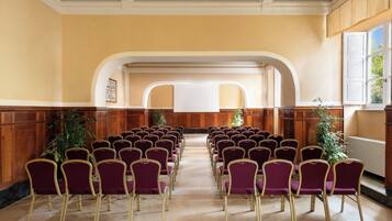 Un salón de conferencias con filas de sillas moradas y paneles de madera en las paredes.