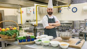 A chef in a kitchen with various vegetables, bowls, and cooking utensils.
