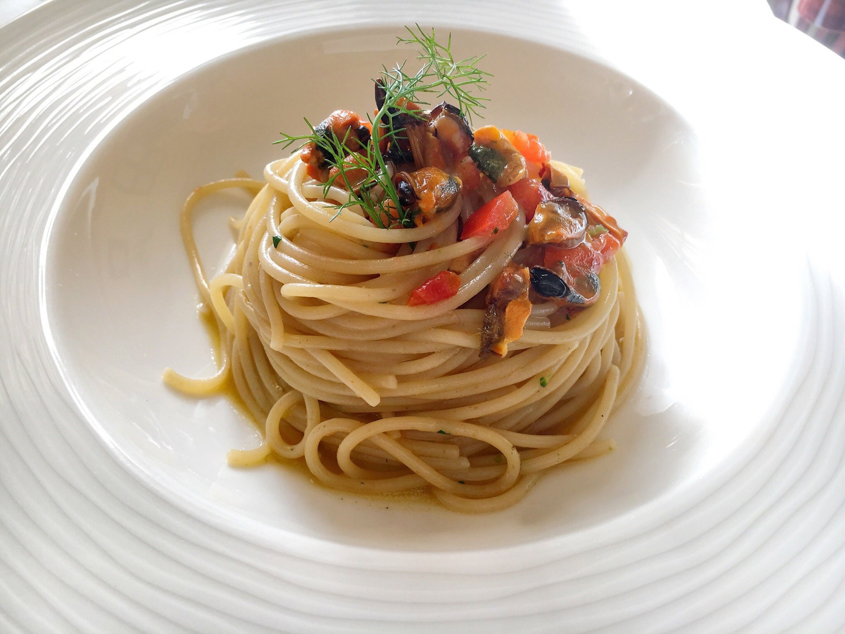 A plate of spaghetti with a tomato-based sauce and herbs.