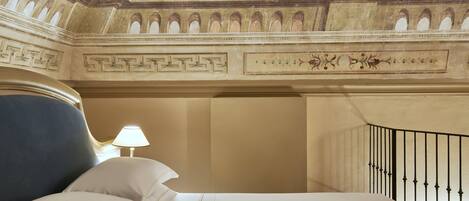 A hotel room with a bed, a nightstand with a lamp, and a decorative ceiling.