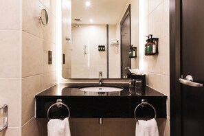 A modern bathroom with a large mirror, a black countertop, a sink, and two towel rings. - voco Belfast by IHG (Belfast)