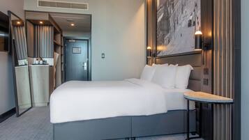 A modern hotel room with a large bed, a small table, and a cityscape mural on the wall.