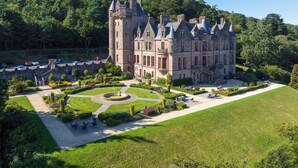 A large, historic stone castle with multiple towers and turrets, surrounded by well-maintained gardens and a manicured lawn. - voco Belfast by IHG (Belfast)