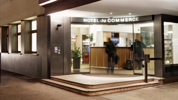 Der Eingang zum HOTEL du COMMERCE mit einer Rezeption und einer Glastür.