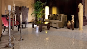 A modern lobby with a sofa, a coffee table, a potted plant, a candelabra, and a large vase. - c-hotels Fiume (Rome)