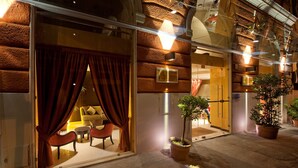 A hotel entrance with a glass door, a seating area with a sofa and chairs, and potted plants outside. - c-hotels Fiume (Rome)