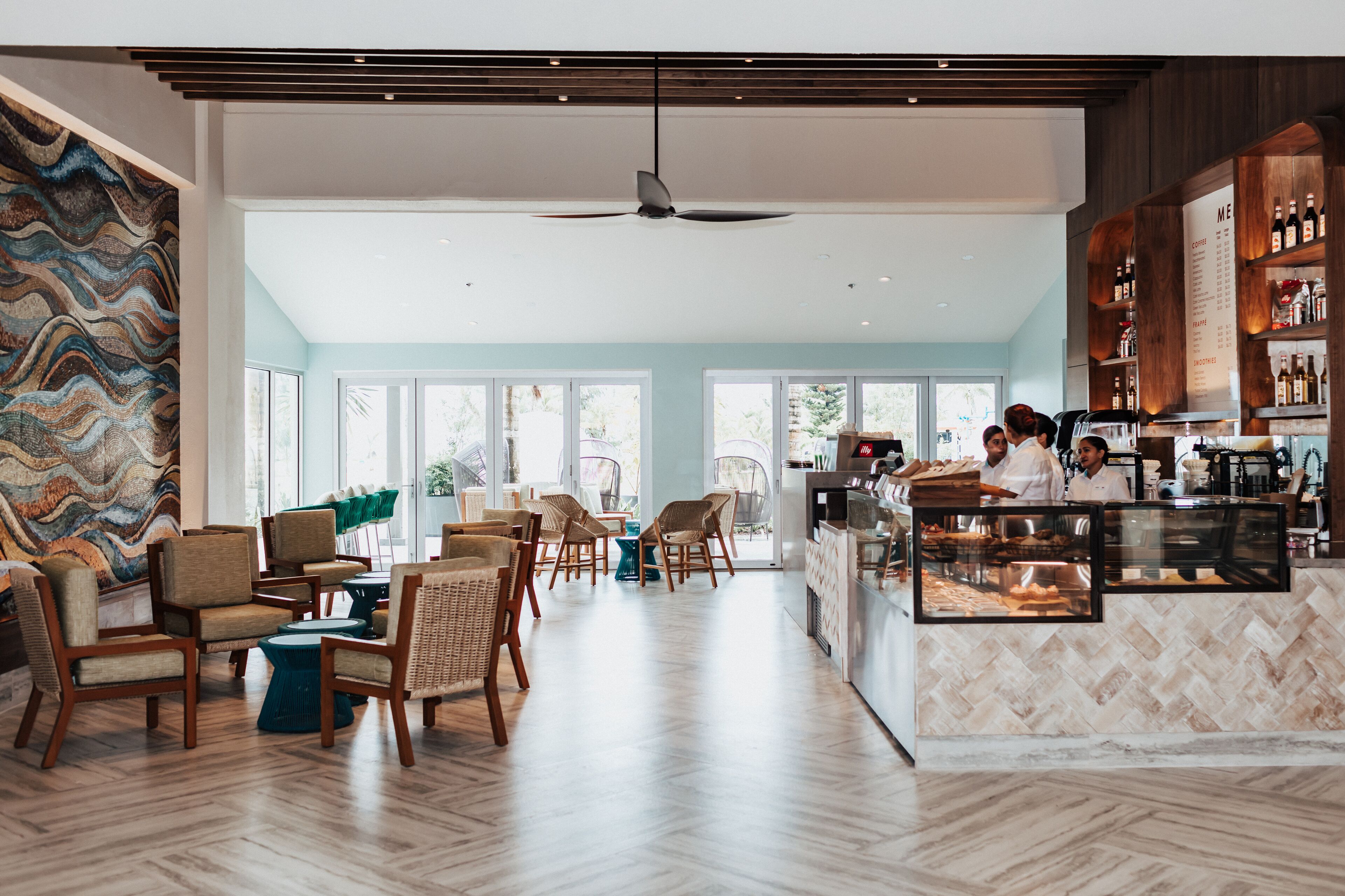 A modern cafe with wooden furniture, a central seating area, and a bar counter with a menu.