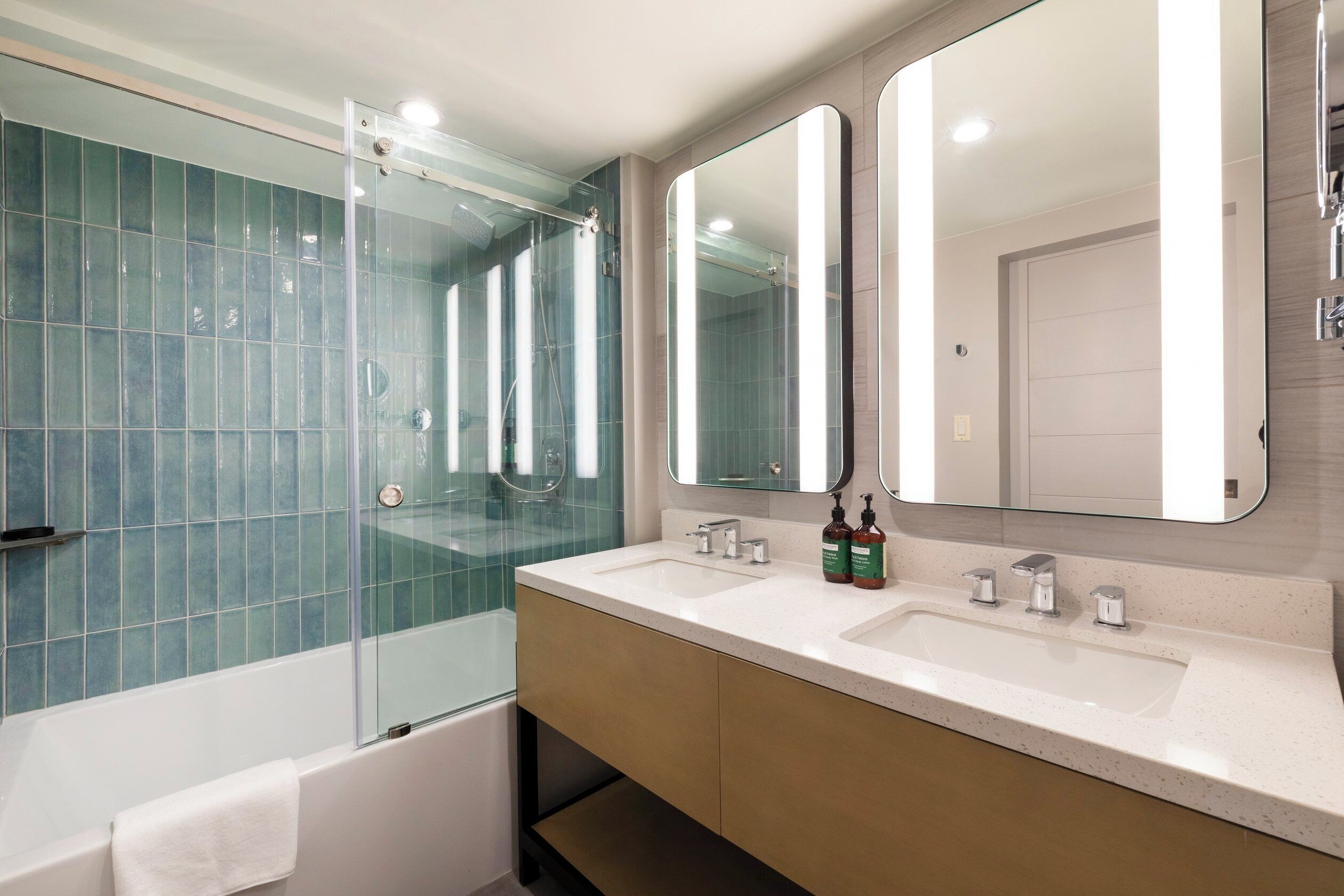 A modern bathroom with a glass-enclosed shower, two sinks, and a large mirror.