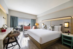 Una habitación de hotel moderna con una cama grande, un escritorio y un balcón con vistas.
