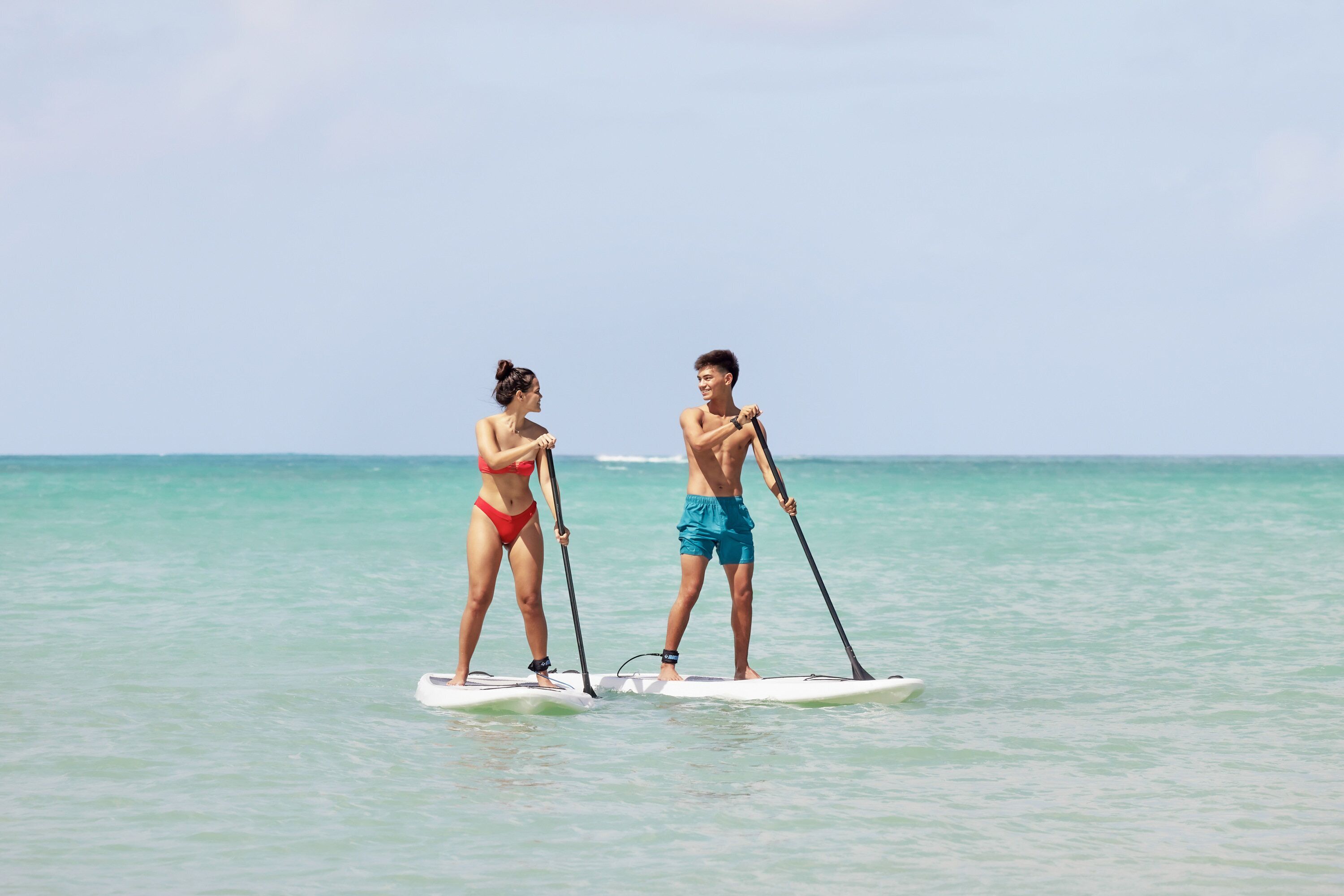 Two people paddleboarding on a calm sea.