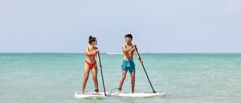 Two people paddleboarding on a calm sea.