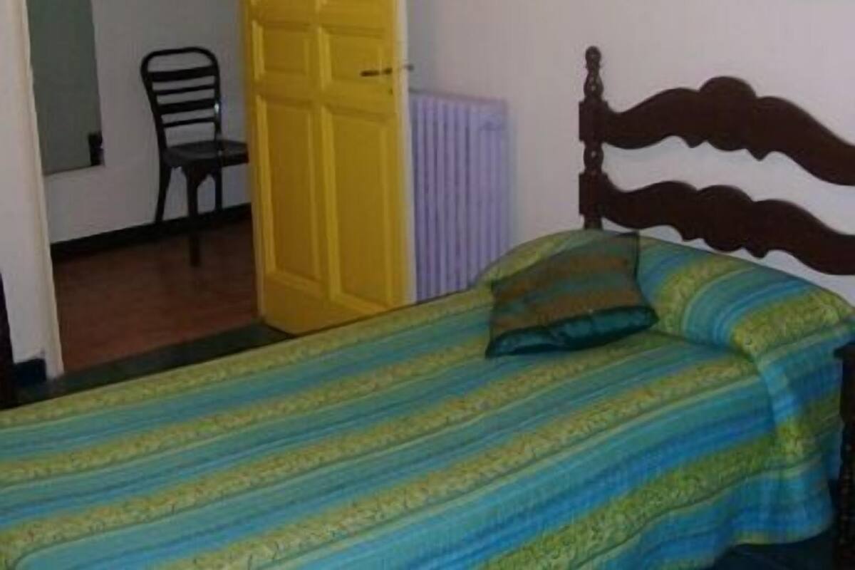 Un dormitorio con una cama, una silla y una puerta amarilla.