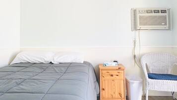 Une chambre à coucher comprenant un lit, une table de chevet, une chaise et un appareil de climatisation.
