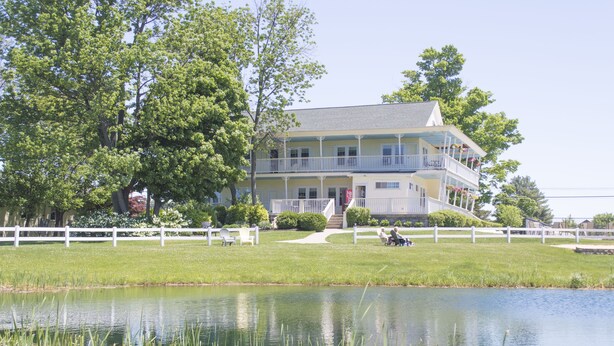 A two-story building with a balcony, a lawn, and a pond. - Sun N Sand Resort (South Haven)