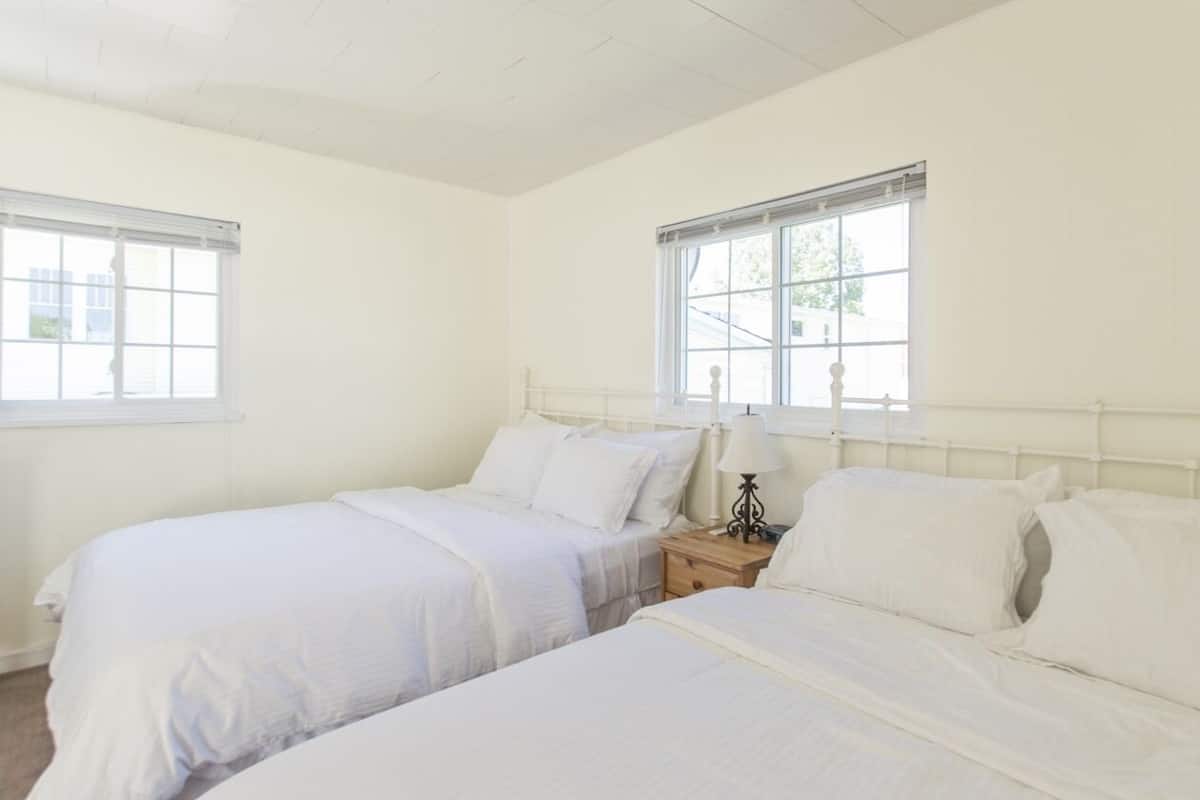A room with two single beds, a bedside table with a lamp, and a window.