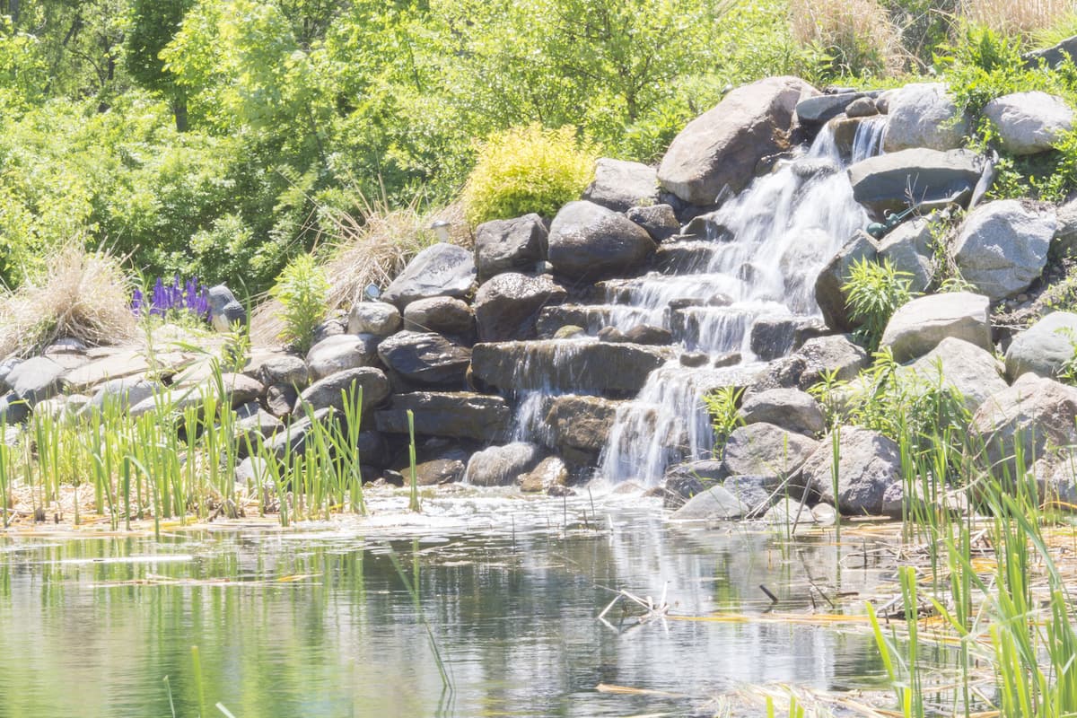 A natural landscape with a waterfall, rocks, and greenery.