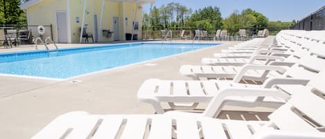 Piscina con sillones blancos y una zona cubierta con puertas.