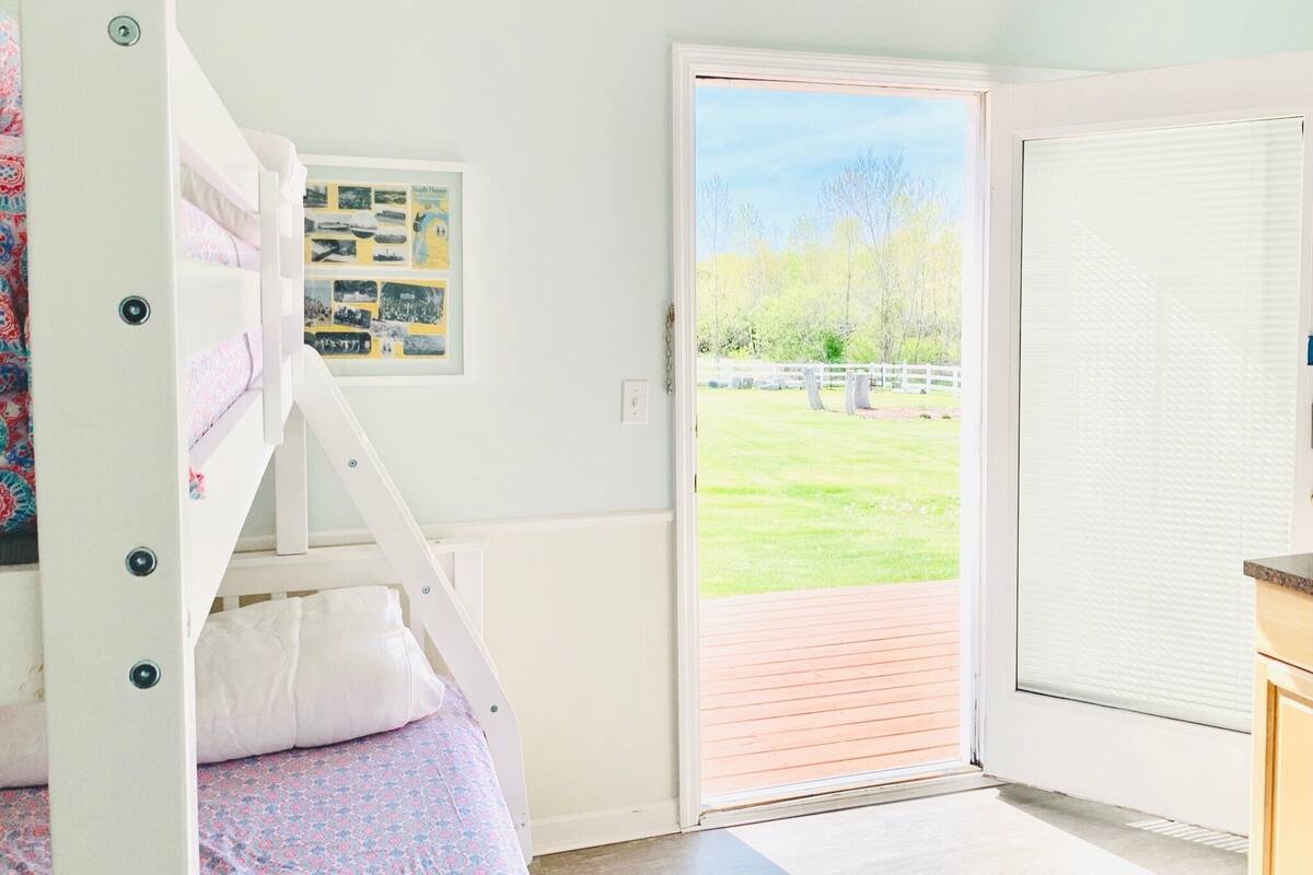 A bedroom with a bunk bed, a door leading to a balcony, and a framed photo on the wall.