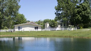 A lakeside property with a white fence, a house with a gabled roof, and a small dock extending into the water. - Sun N Sand Resort (South Haven)