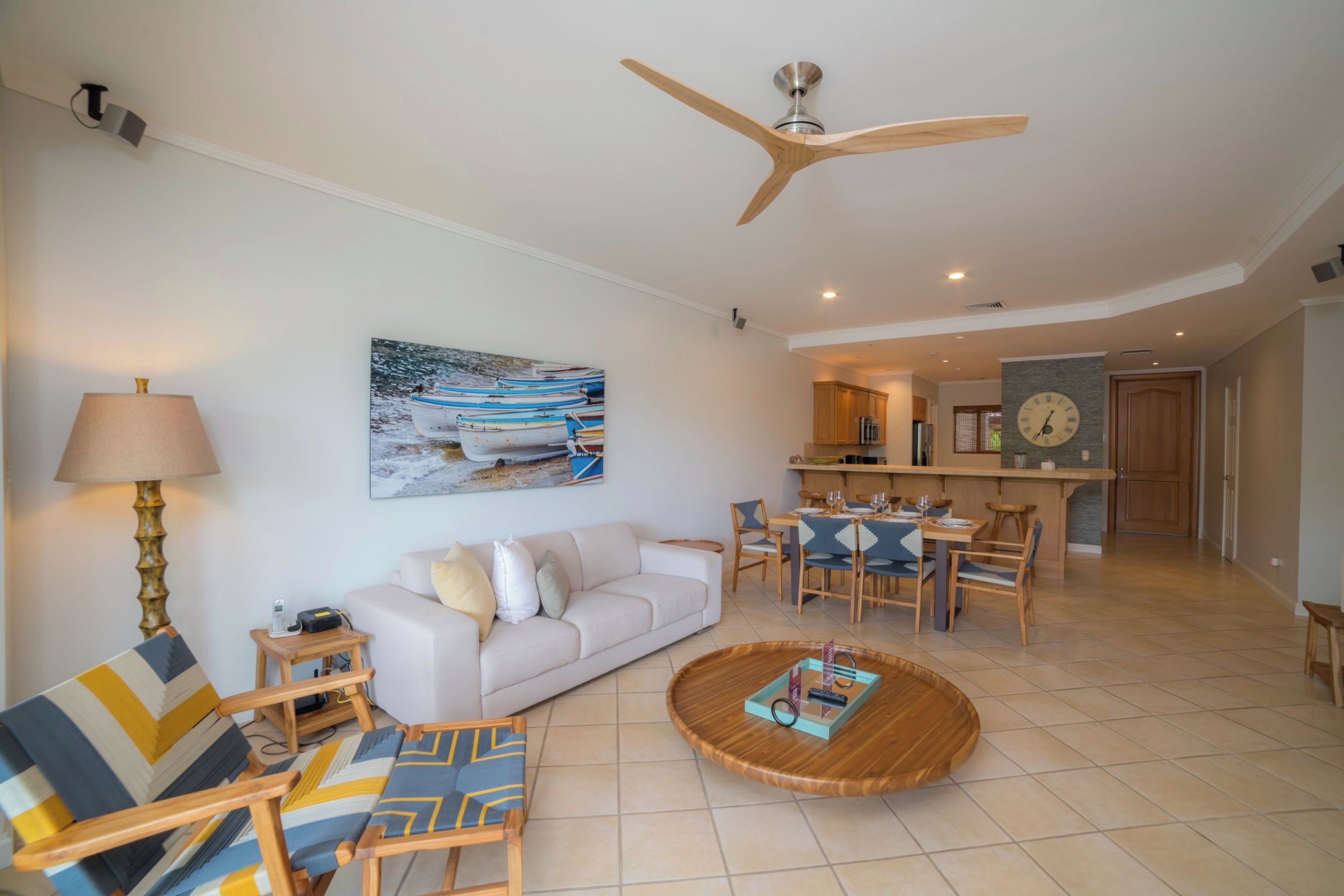 A modern living room with a sofa, chairs, a coffee table, and a ceiling fan.