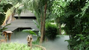 A pathway leading to a traditional-style building surrounded by lush greenery and a bamboo fence. - Riyuegu Hotsprings Resort (Xiamen)