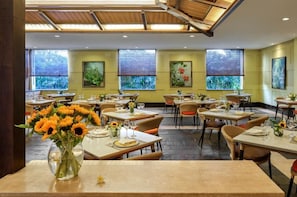 A restaurant with multiple tables, each set with plates, glasses, and sunflowers. - Riyuegu Hotsprings Resort (Xiamen)