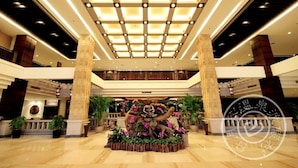 A spacious lobby with a central decorative fountain, high ceilings with recessed lighting, and a modern architectural design. - Riyuegu Hotsprings Resort (Xiamen)