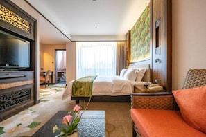 A hotel room with a bed, a television, a desk, a chair, and a painting on the wall. - Riyuegu Hotsprings Resort (Xiamen)