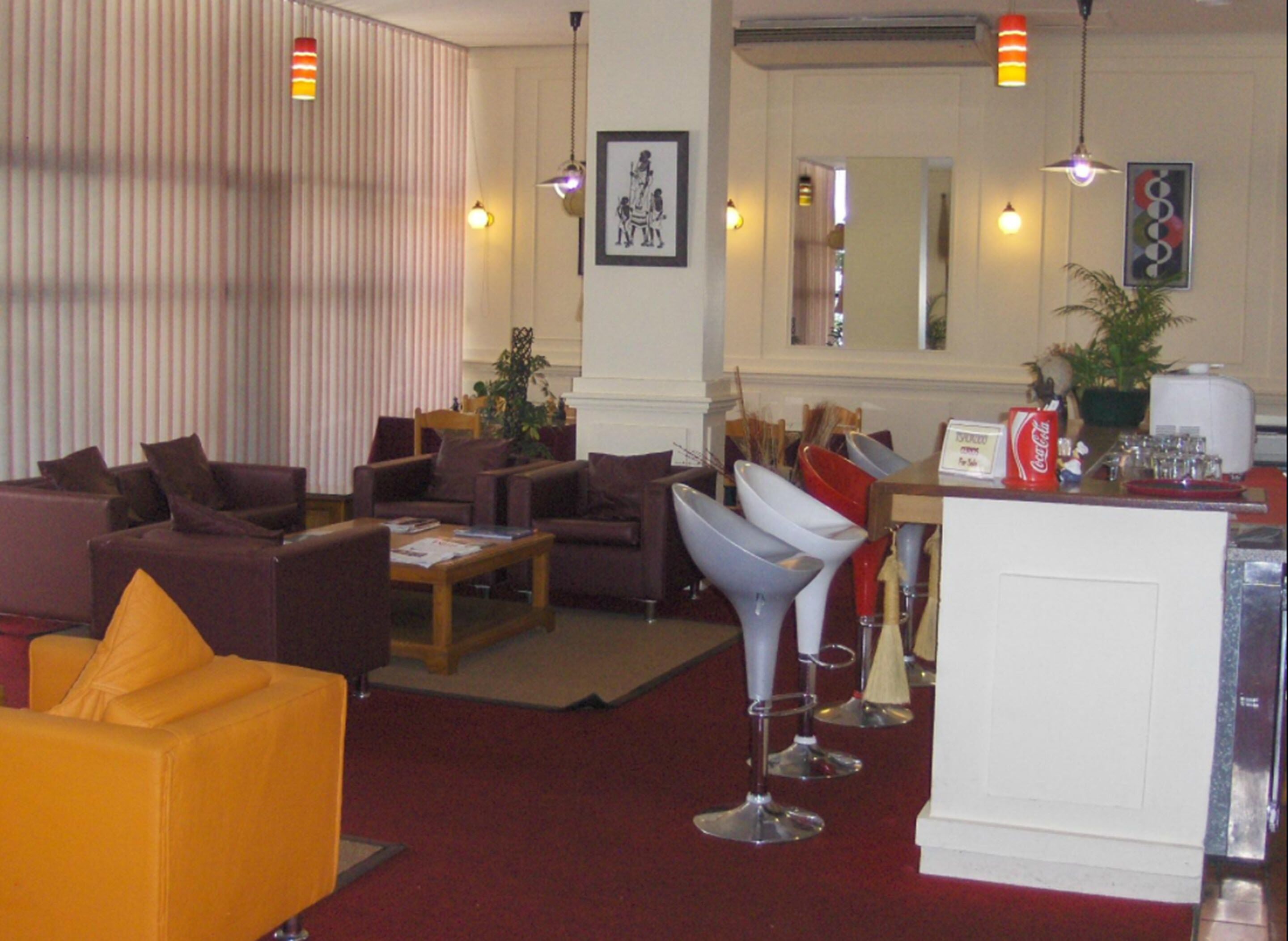 Un vestíbulo de hotel con zonas de estar, un mostrador de recepción y un espejo grande.