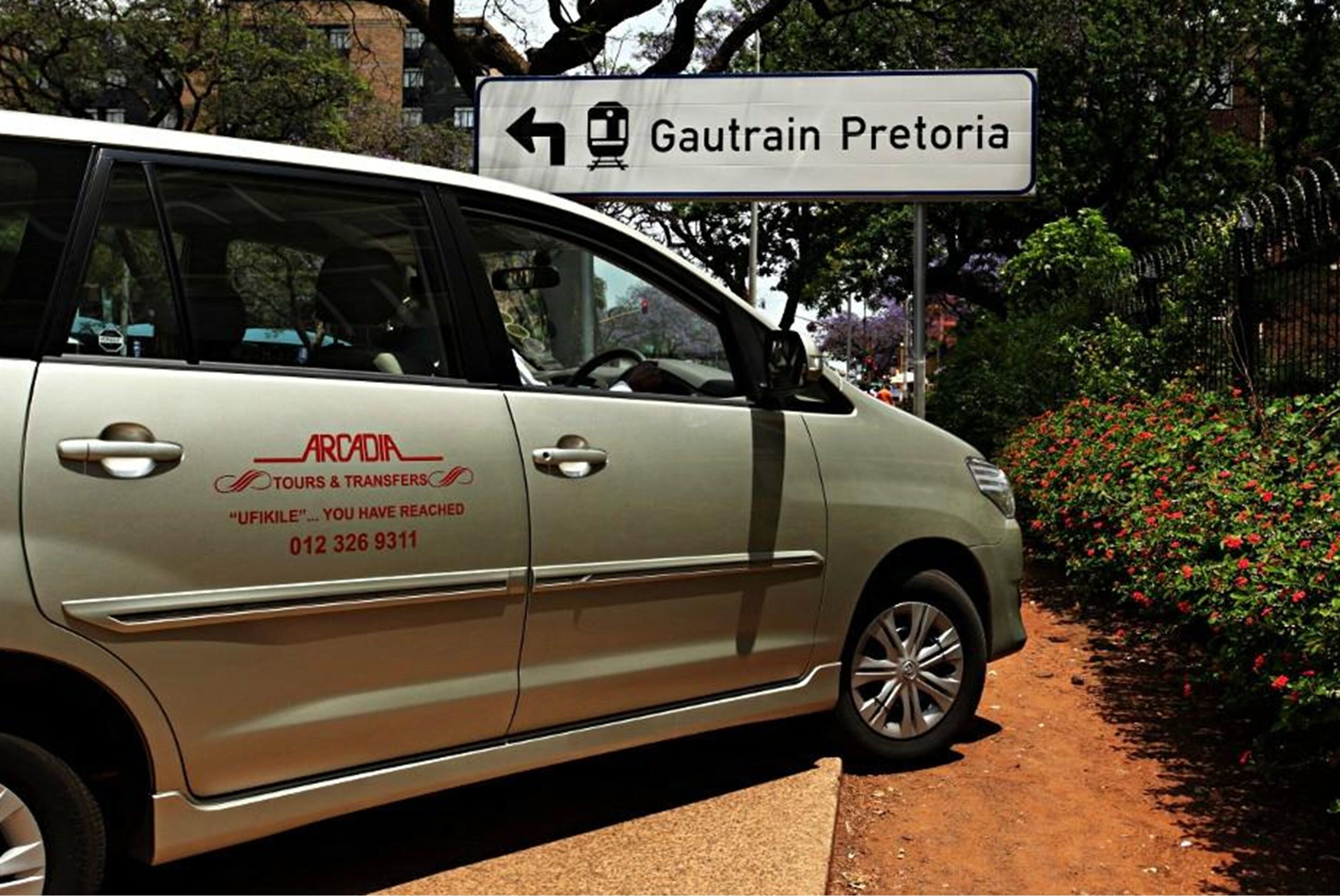 Ein Reisebus mit einem Schild, das 'Gautrain Pretoria' und den Firmennamen 'ARCADIA TOURS & TRANSFERS' zeigt.