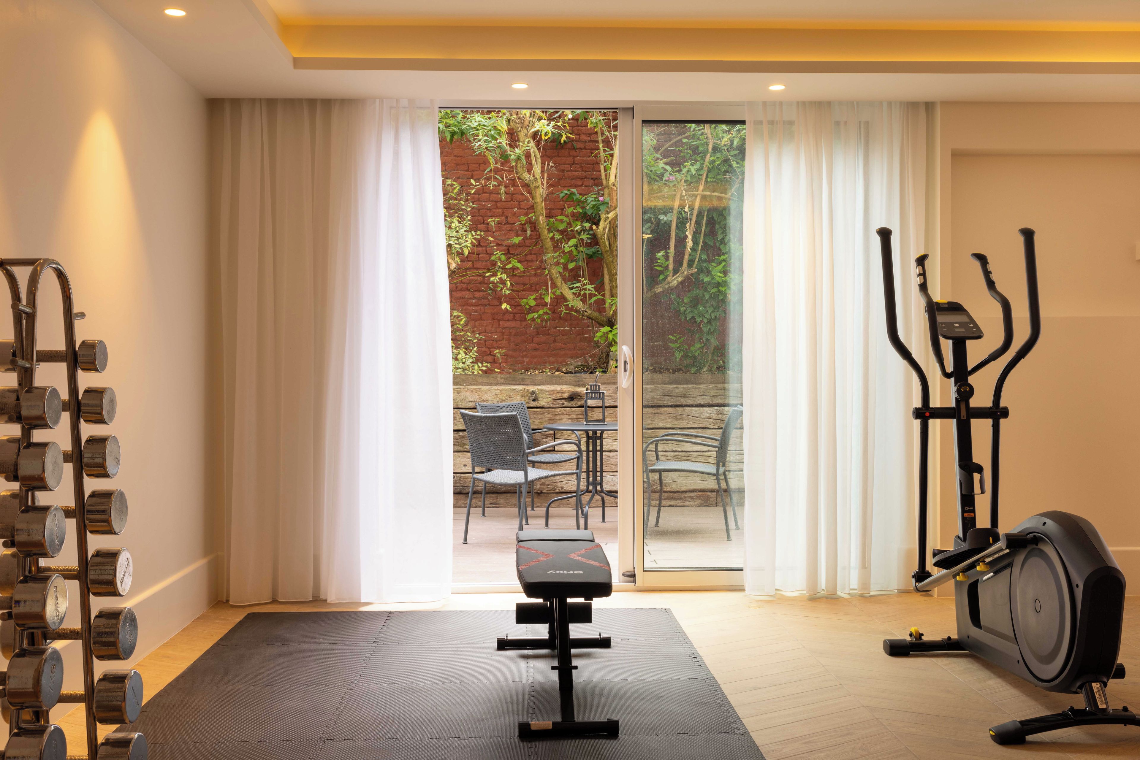 A home gym with a stationary bike, a bench press, and a set of dumbbells.