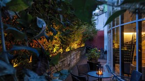 An outdoor patio with a brick wall, potted plants, and a table with chairs. - The Augustin (Brussels)