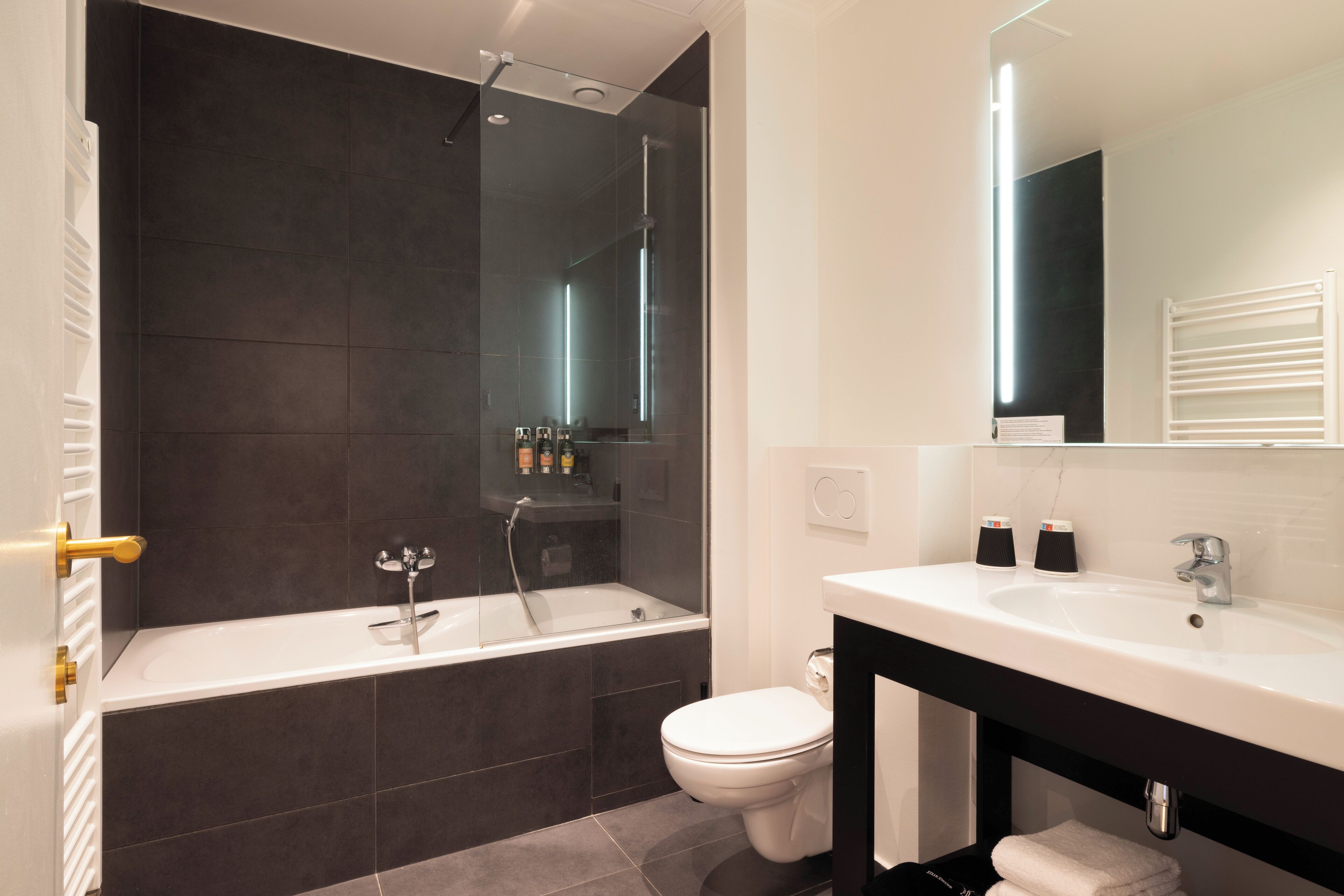 Un baño moderno con bañera, inodoro y tocador con espejo.