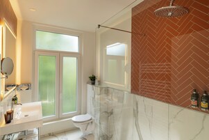 A modern bathroom with a glass shower enclosure, a white toilet, and a marble vanity.
