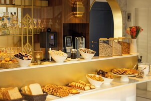 Un buffet con diverse pietanze, tra cui pane, pasticcini e un angolo caffè.