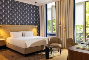 Een moderne hotelkamer met een groot bed, een zithoek met een tafel en uitzicht op groen.