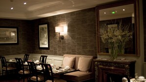A dining area with a brick wall, a sofa, and a mirror. - Hotel de la Treille (Lille)