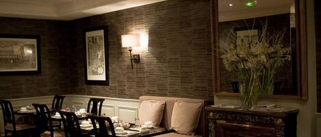 A dining area with a brick wall, a sofa, and a mirror.