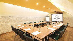 A conference room with a long table, chairs, water bottles, and a projector screen displaying "Regent Hotel". - Hotel Regent (Kraków)