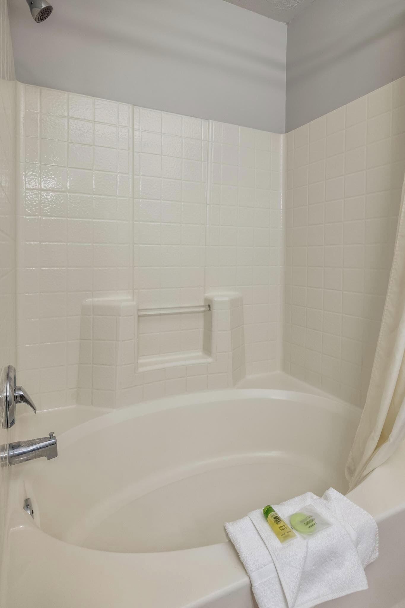 A bathroom with a bathtub, a showerhead, and a towel rack.