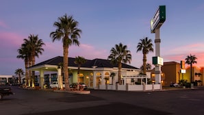 A hotel with a covered outdoor area, palm trees, and a sign indicating it is a St. Louis Inn & Suites. - St. George Inn & Suites (St. George)