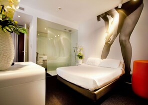 A modern hotel room with a large bed, a glass shower enclosure, and a decorative sculpture. - Green Hotel Motel (Vergiate)