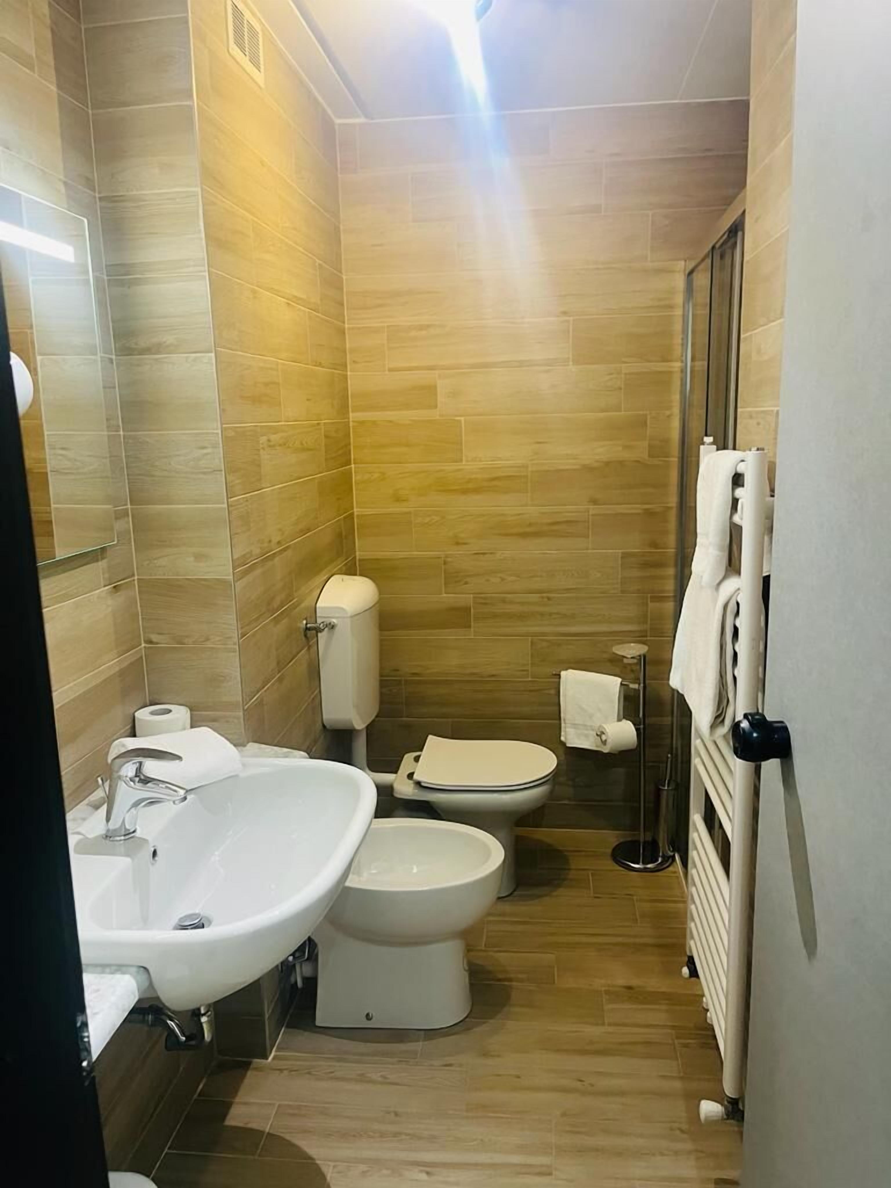 Une petite salle de bain comprenant un lavabo, deux toilettes et un radiateur.