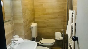 Une petite salle de bain comprenant un lavabo, deux toilettes et un radiateur.