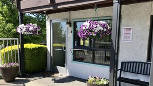 A building entrance with a glass door, potted plants, and a bench. - Sea-Tac Airport Value Inn (Des Moines)
