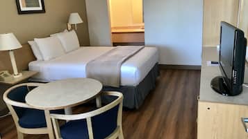 A hotel room with a bed, bedside lamps, a desk with a computer, a chair, and a television.