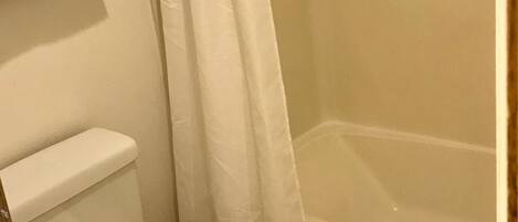 A bathroom with a toilet, a bathtub, and a shower curtain.