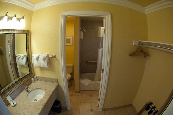 A bathroom with a sink, mirror, and a shower area. - Deer Haven Inn (Pacific Grove)