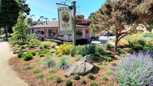 A sign for the Inn Suites with a clear view of the building and surrounding landscaped garden. - Deer Haven Inn (Pacific Grove)